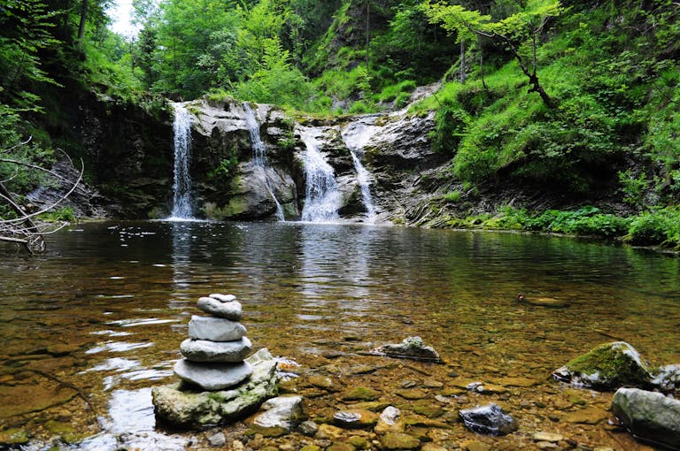 StreameastGG waterfall with serene stone cairn, ideal for nature and travel themes.