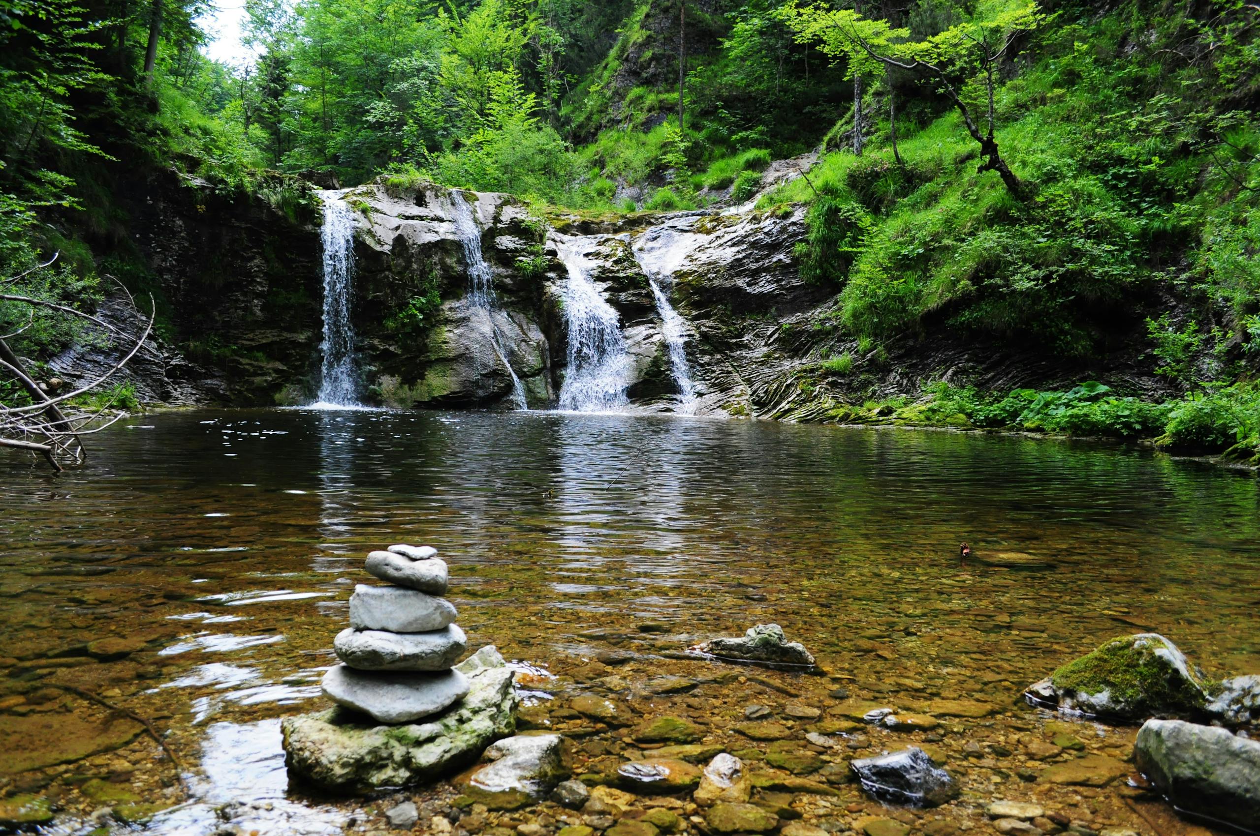 StreameastGG waterfall with serene stone cairn, ideal for nature and travel themes.