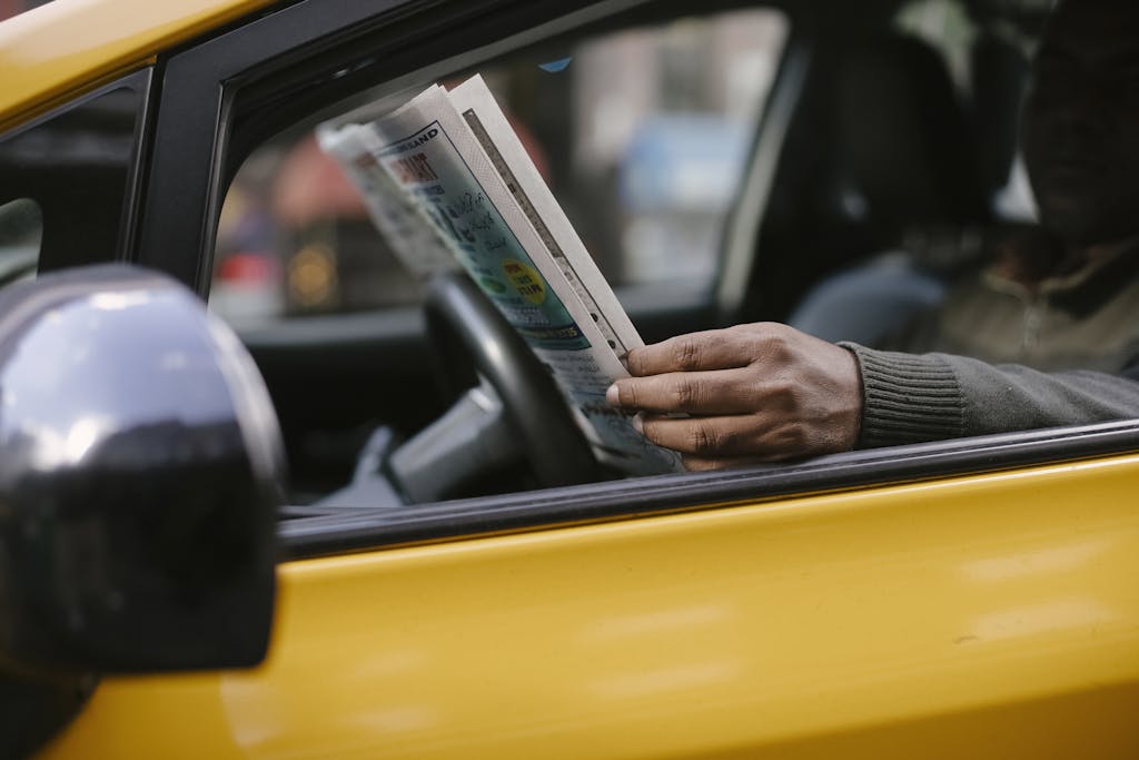 StreameastGG anonymous ethnc male driver reading information in newspaper article while waiting for client