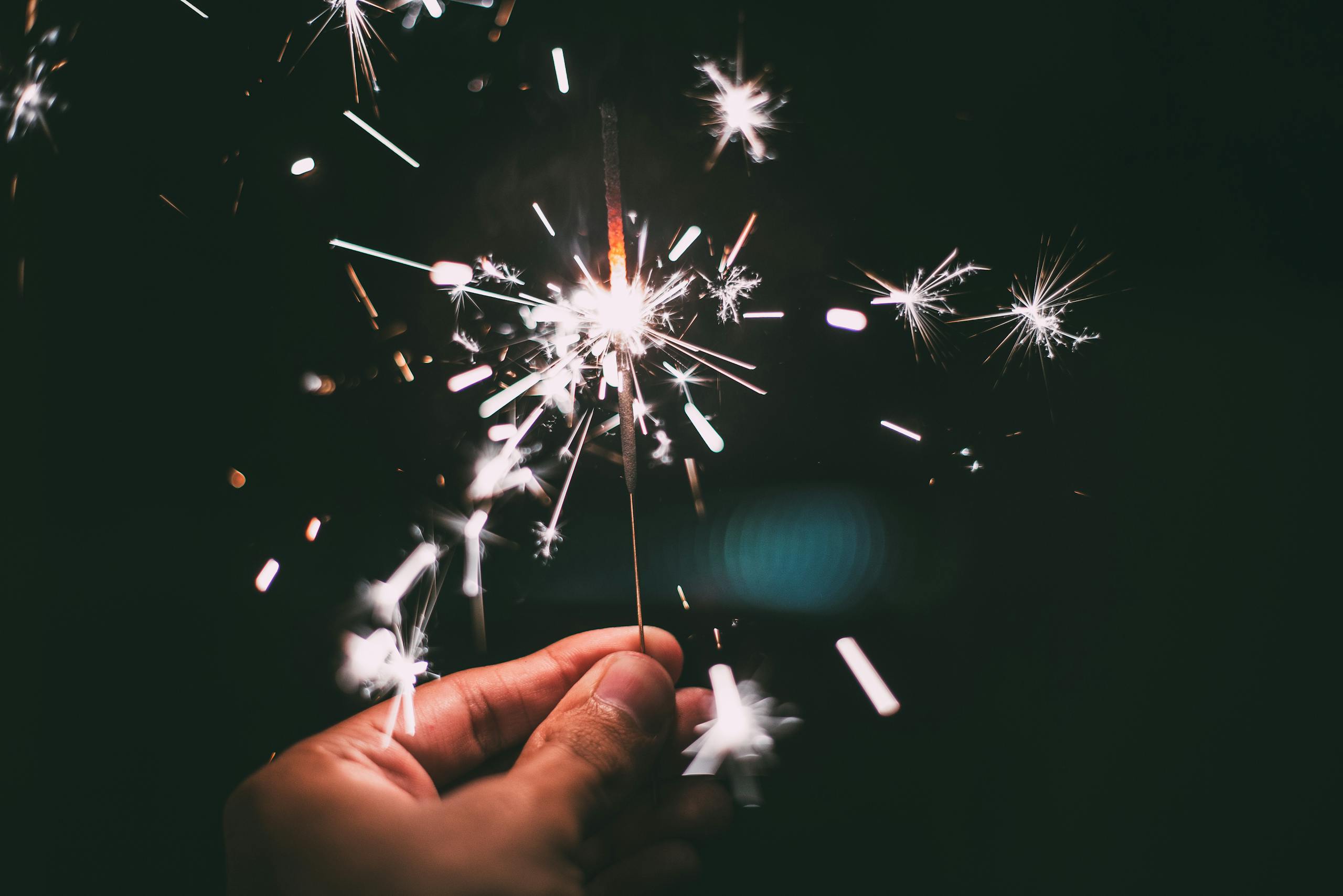 Nerwey A hand holding a sparkler glowing brilliantly in the night, perfect for festive and holiday themes.