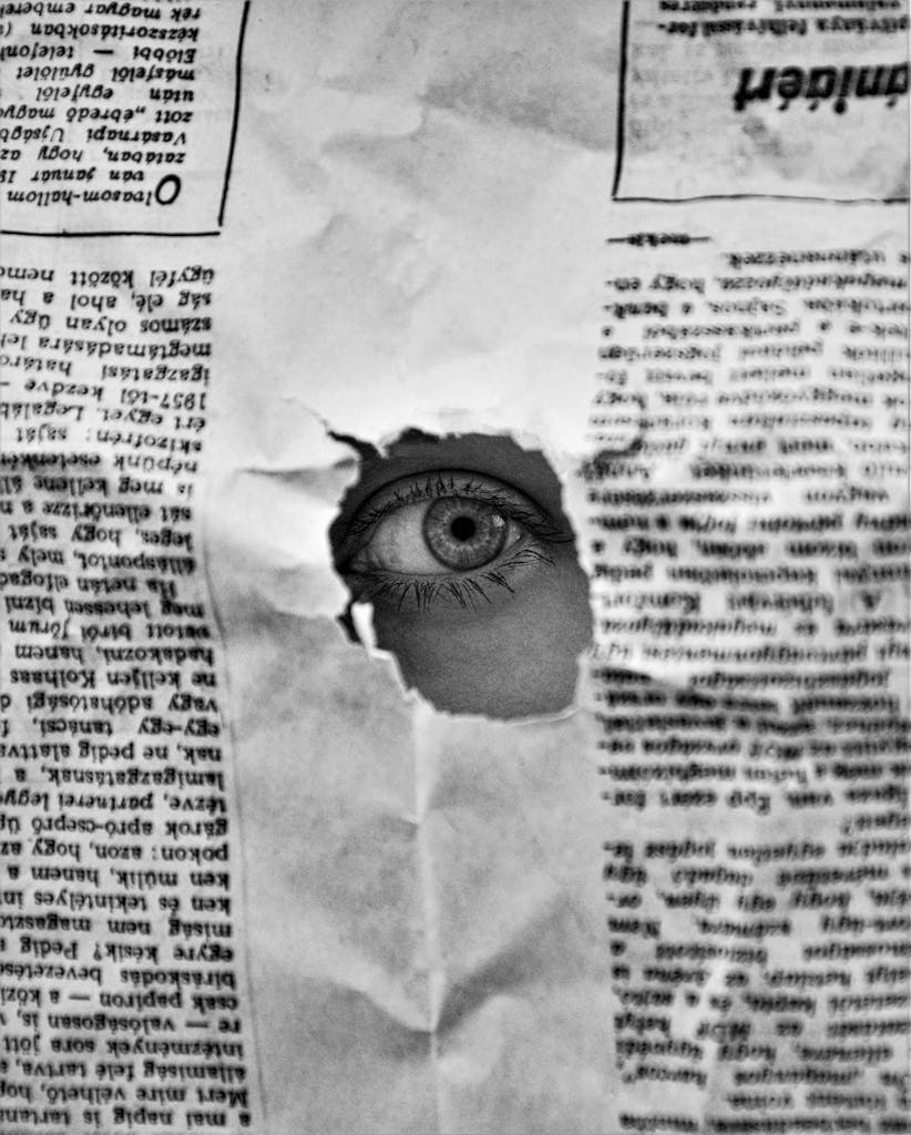 Florissant Newspaper peering through a hole in a black and white newspaper, creating an intriguing visual.