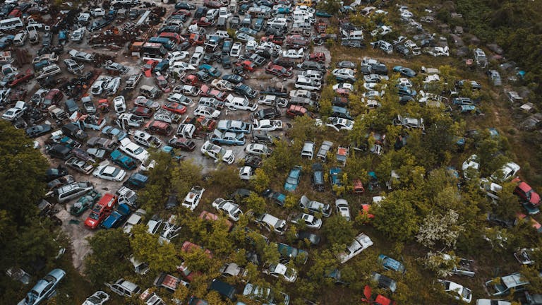 Apna Use Usa Aerial view of abandoned cars in a junkyard surrounded by greenery in Chattanooga.
