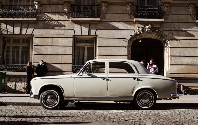 Wheon Grand Theft Auto: A Complete Deep Dive into the Iconic Open-World Phenomenon Classic white car parked on a European street with people nearby, showcasing urban architecture.