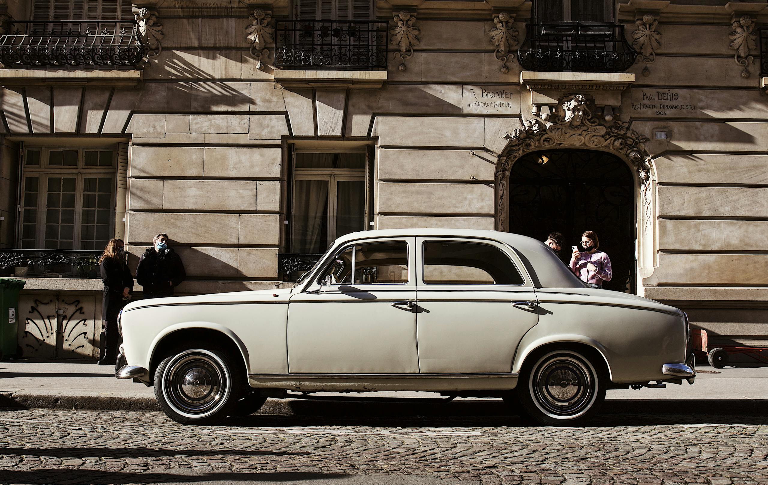 Wheon Grand Theft Auto: A Complete Deep Dive into the Iconic Open-World Phenomenon Classic white car parked on a European street with people nearby, showcasing urban architecture.