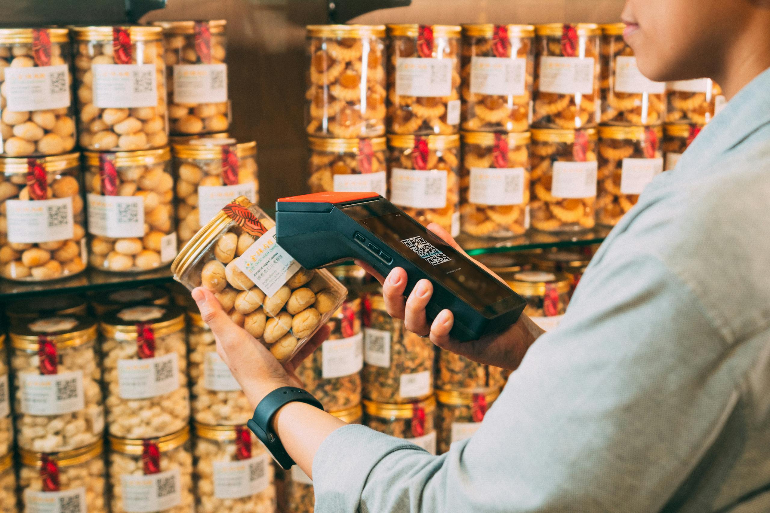 Aurora QR Code Individual scanning QR codes on jars in a store with a handheld device.