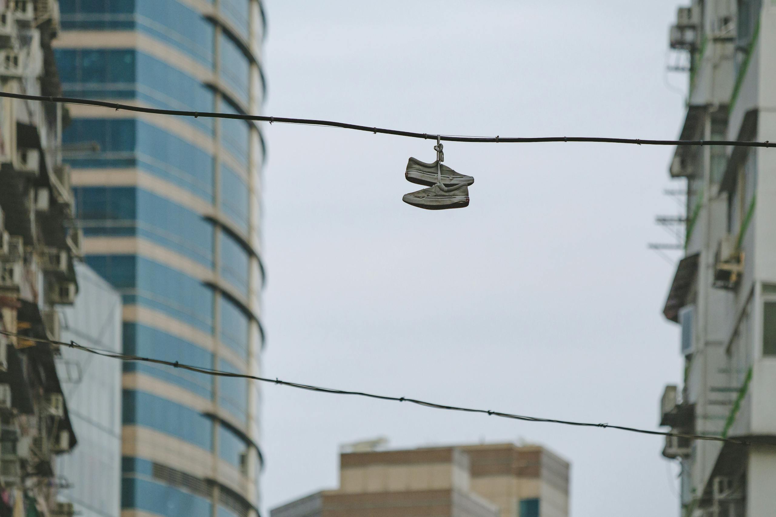 Ronaldo vs Messe in 2026: The Final Chapter of Football’s Greatest Rivalry Sneakers hanging on wire amidst Hong Kong skyscrapers, showcasing urban lifestyle and architecture.
