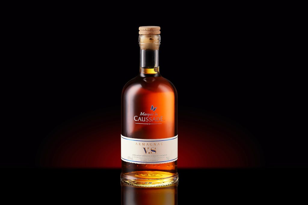 Brandi Loge A bottle of Armagnac VS with a cork, elegantly displayed against a dark background.