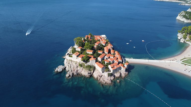 Filmfly com Technology Trends Gonzay Com A breathtaking aerial view of the picturesque Sveti Stefan Island, Montenegro, surrounded by azure waters.
