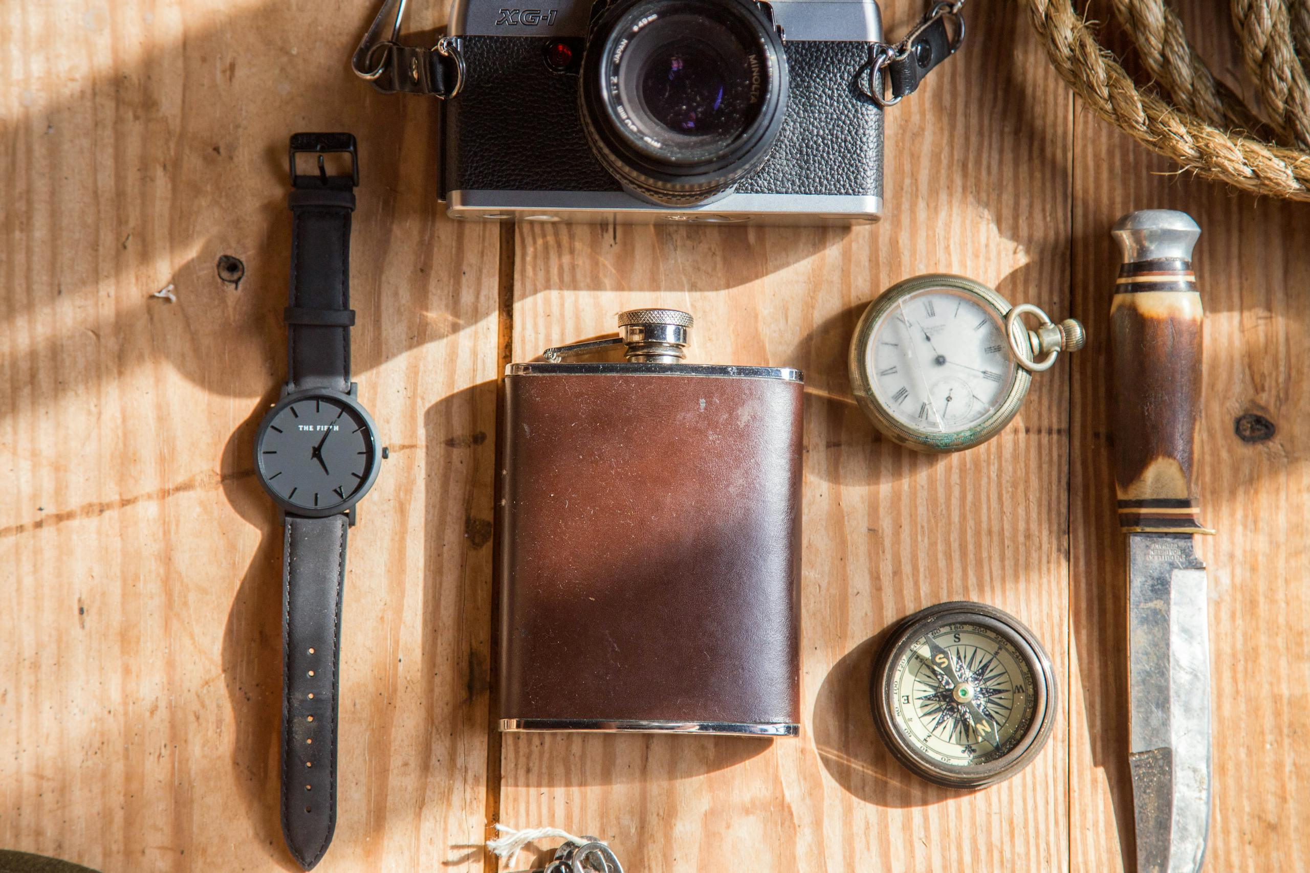 Impupdates.comwow Independence A flat lay of classic items including a camera, pocket watch, and knife on a wooden surface.