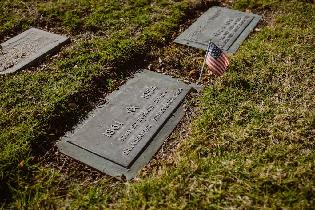Drivers Death USA A gravestone adorned with an American flag in a green cemetery, symbolizing honor and remembrance.