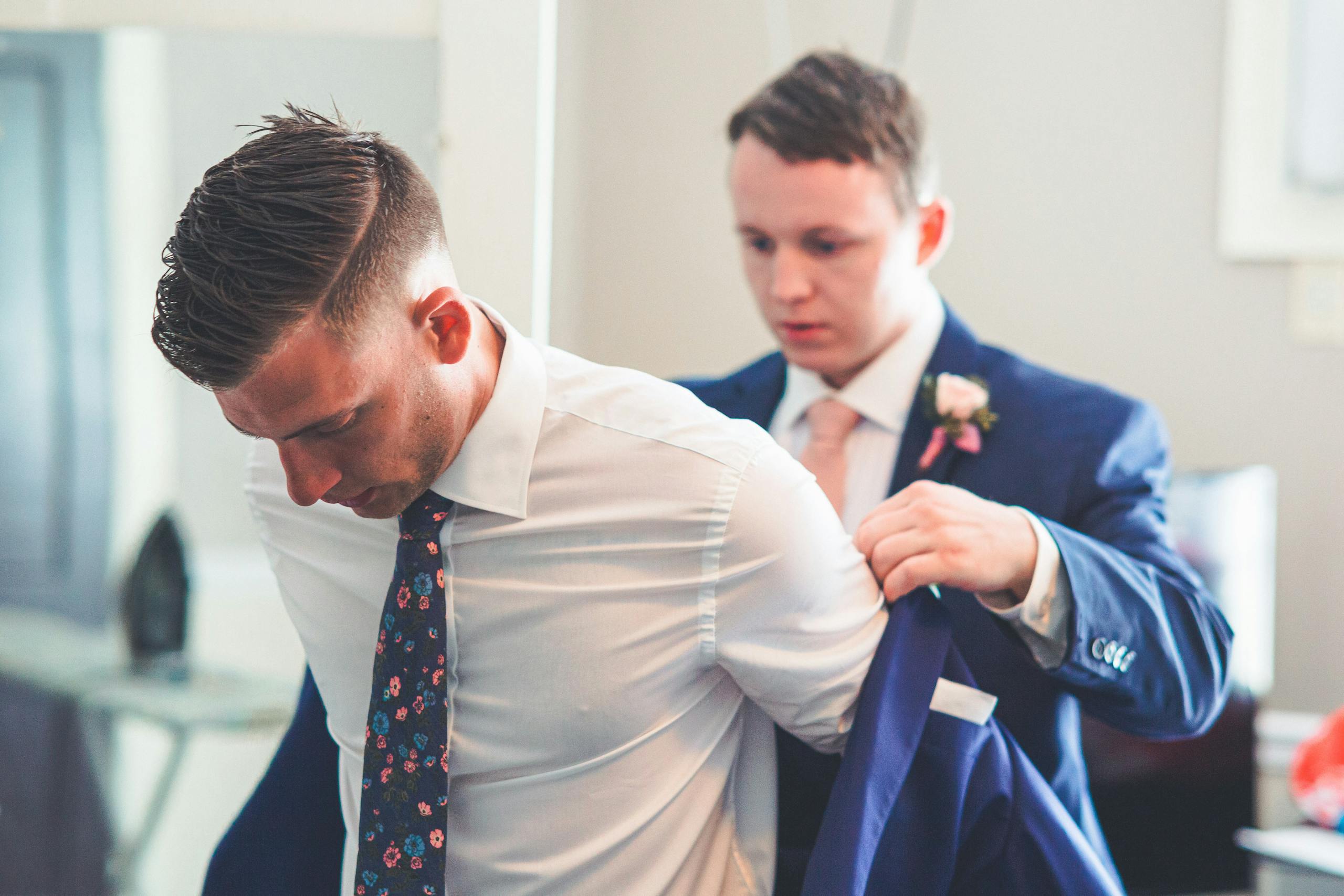 Blazertje A groom gets assistance with his jacket from the best man on his wedding day.