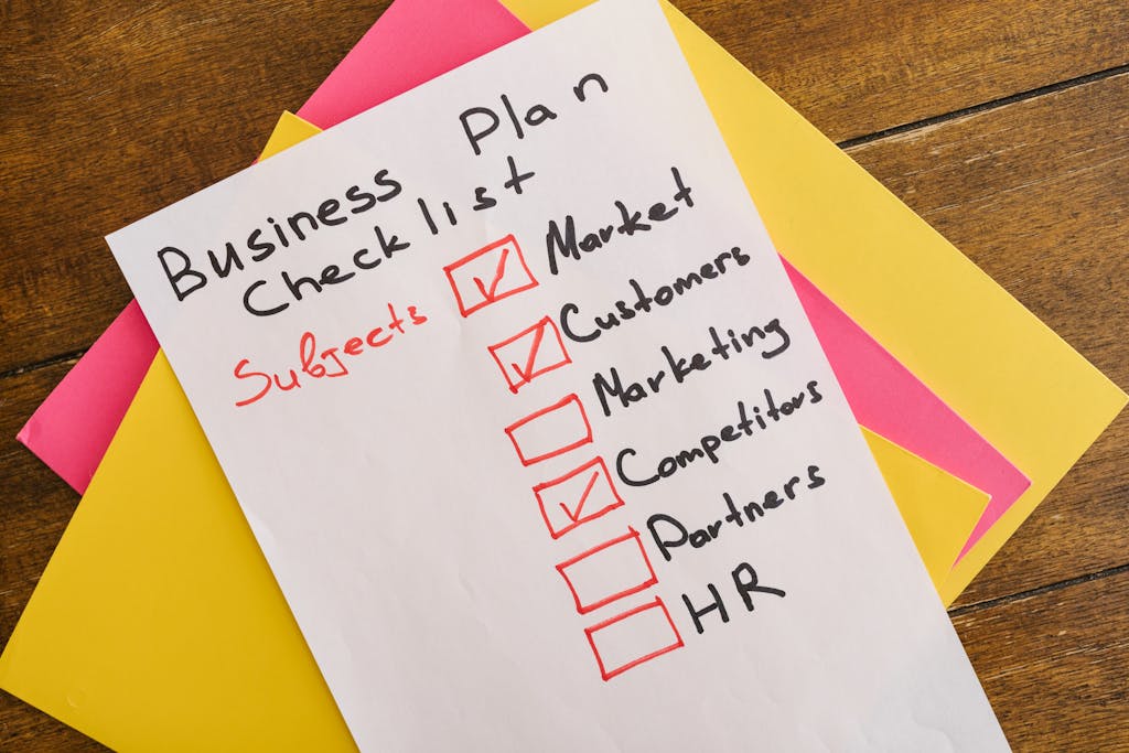 Binuscx A handwritten business plan checklist on a table with colorful papers indicating important topics for startups.