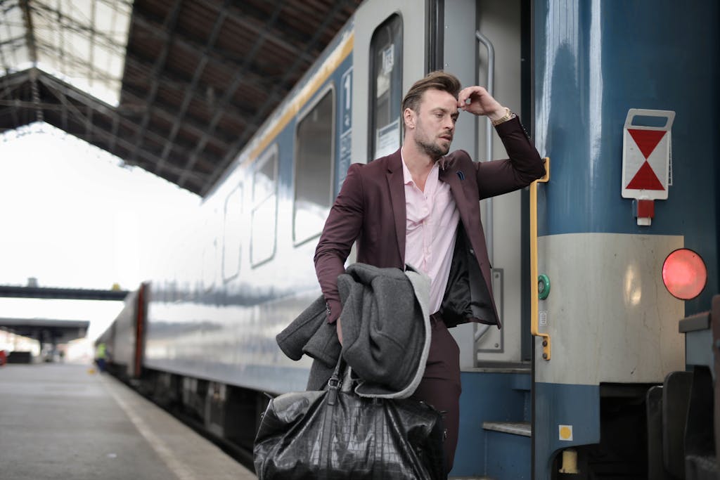 Blazertje A man in a suit, carrying bags, looks stressed as he boards a train at a railway station.