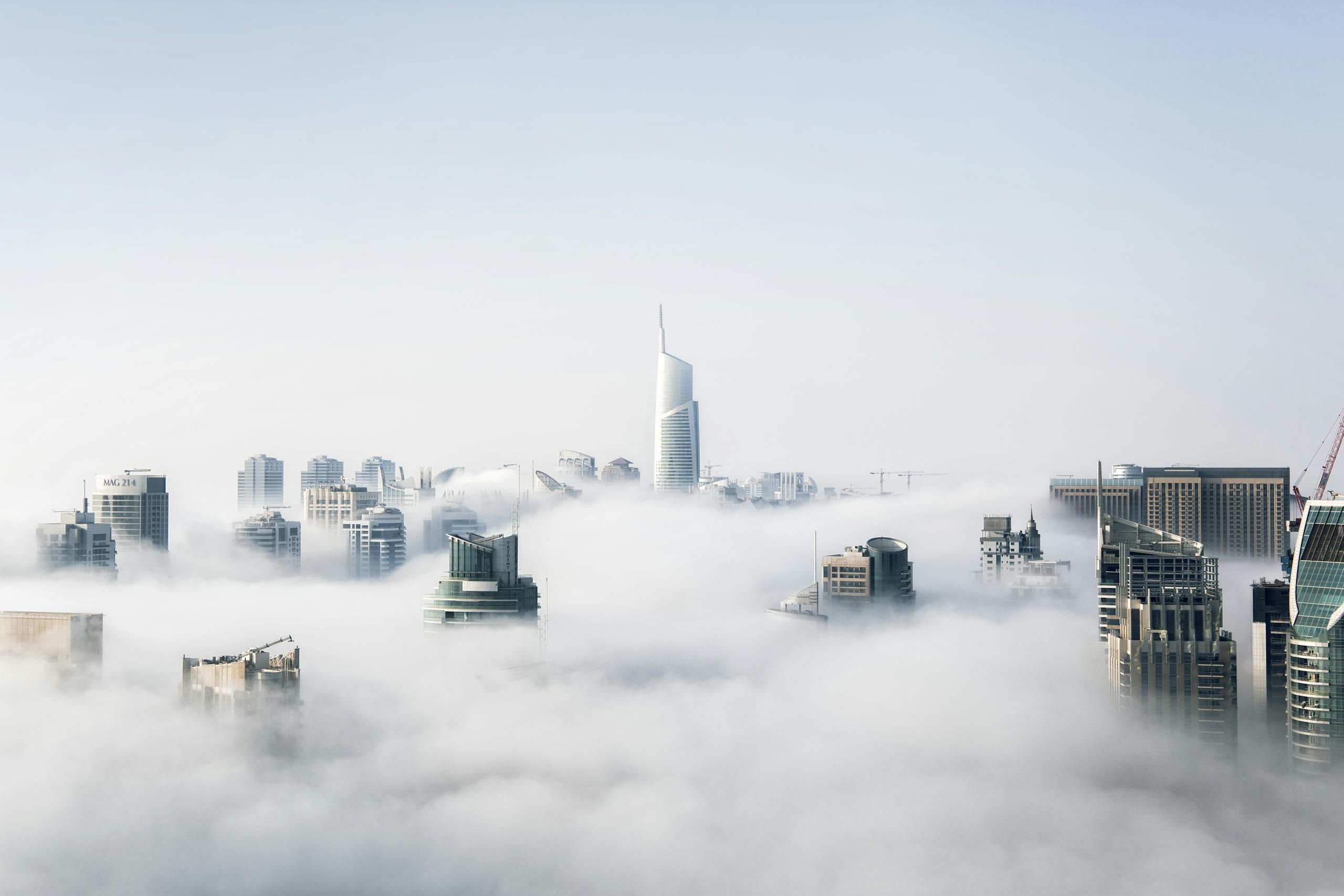 Epcylo nA stunning view of Dubai skyscrapers emerging through a blanket of fog, showcasing modern architecture.