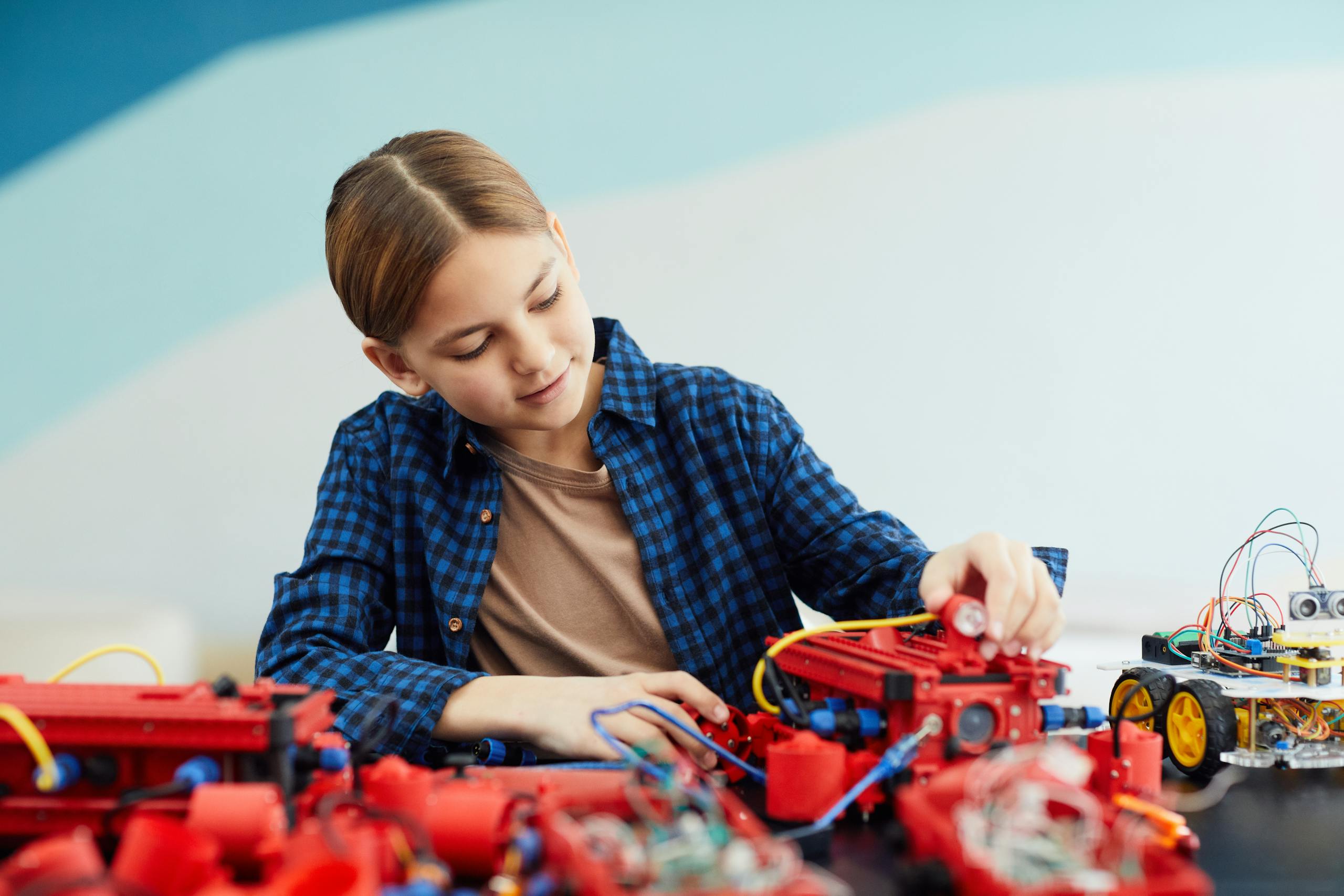 Auztron Bot A teenage girl engaged in assembling a robotics project with various electronic components.
