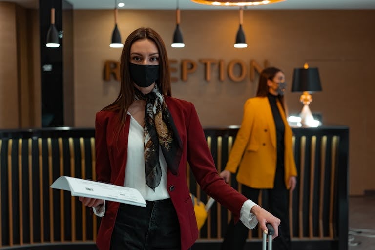 Check Whether 61479 Is Divisible by 81 A woman in a mask stands at a hotel reception desk holding paper, welcoming service