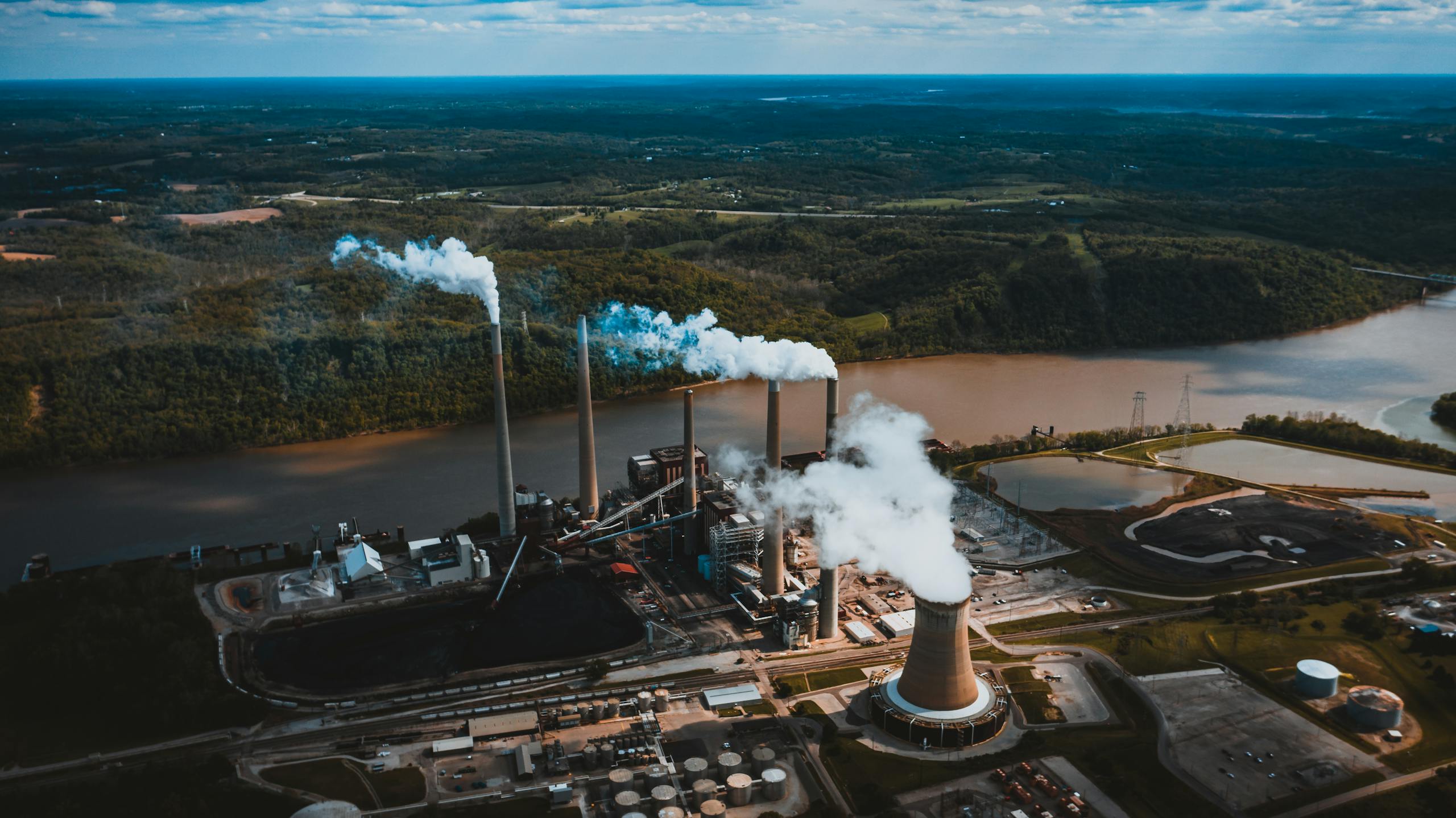 Lewis Center Ohio Champion Trees Aerial photograph of a power plant emitting smoke by a river surrounded by lush greenery in North Bend, Ohio.