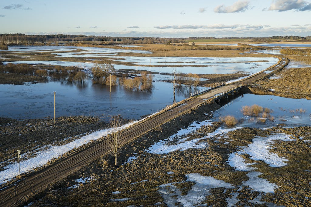 Trencher for Drainage Aerial view of a flooded dirt road in winter, Skārdupes, Latvia.