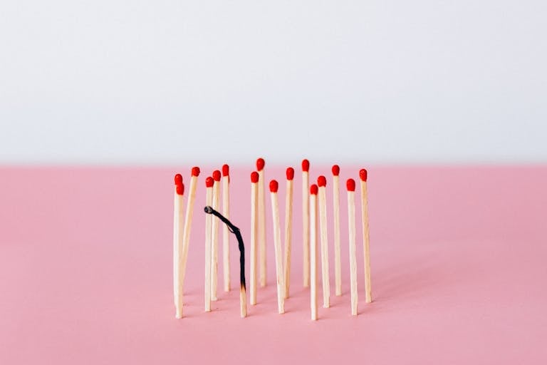 Spaietacle Artistic representation of burnout with matchsticks on a pink surface in a studio setting.