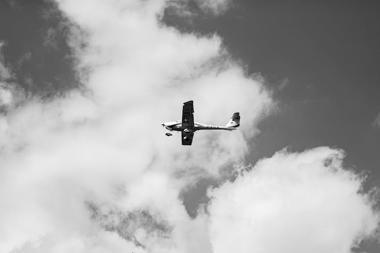 adsy.pw/hb5 Black and white photograph of a Cessna flying amidst clouds, showcasing its mid-air elegance.