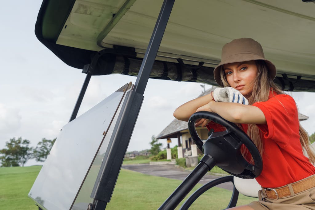 Golf Cart Seat Covers Chic woman in hat sitting in a golf cart on a lush green golf course.
