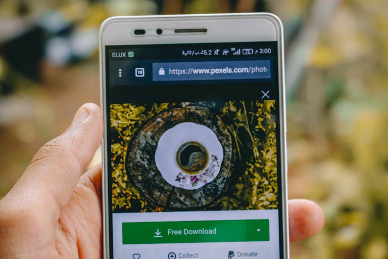 URLWO Close-up of a smartphone showing a coffee cup image on a screen outdoors.