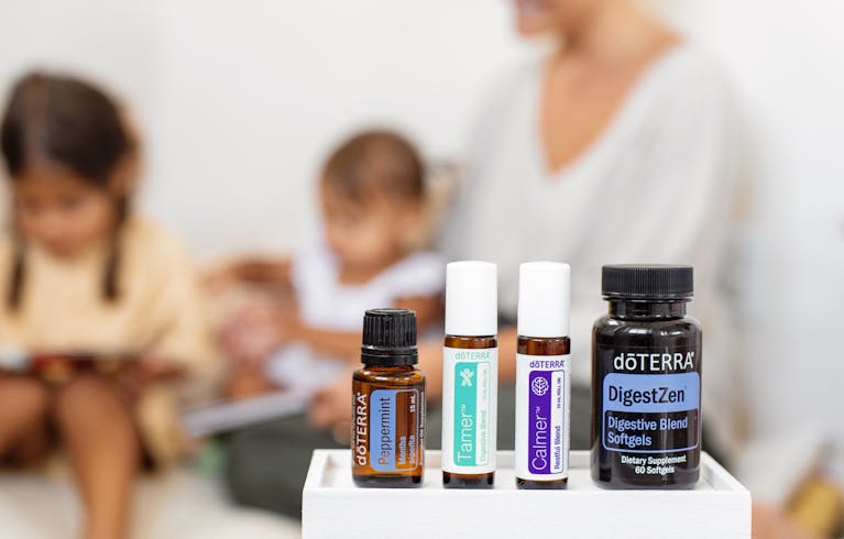Calmered Calmered Close-up of doTERRA essential oils and supplements with people in a blurred background.