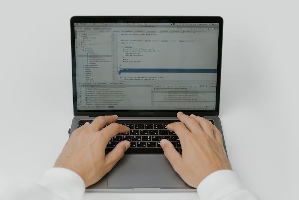 Knowledge Base Software Close-up of hands coding on a laptop, showcasing software development in action.