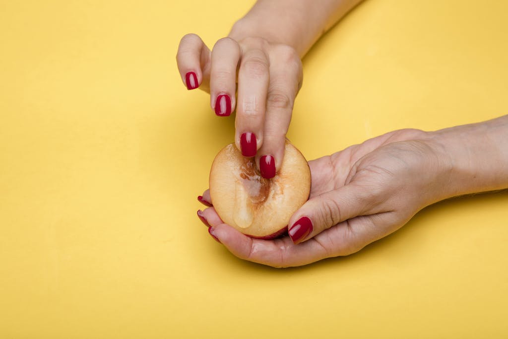Simbramento Creative conceptual image featuring hands holding and touching a peach on a vibrant yellow background.