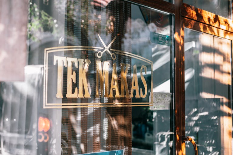 TEK-102 Glass wall of modern barbershop with reflection on surface and creative inscription placed near door on street in city under sunlight