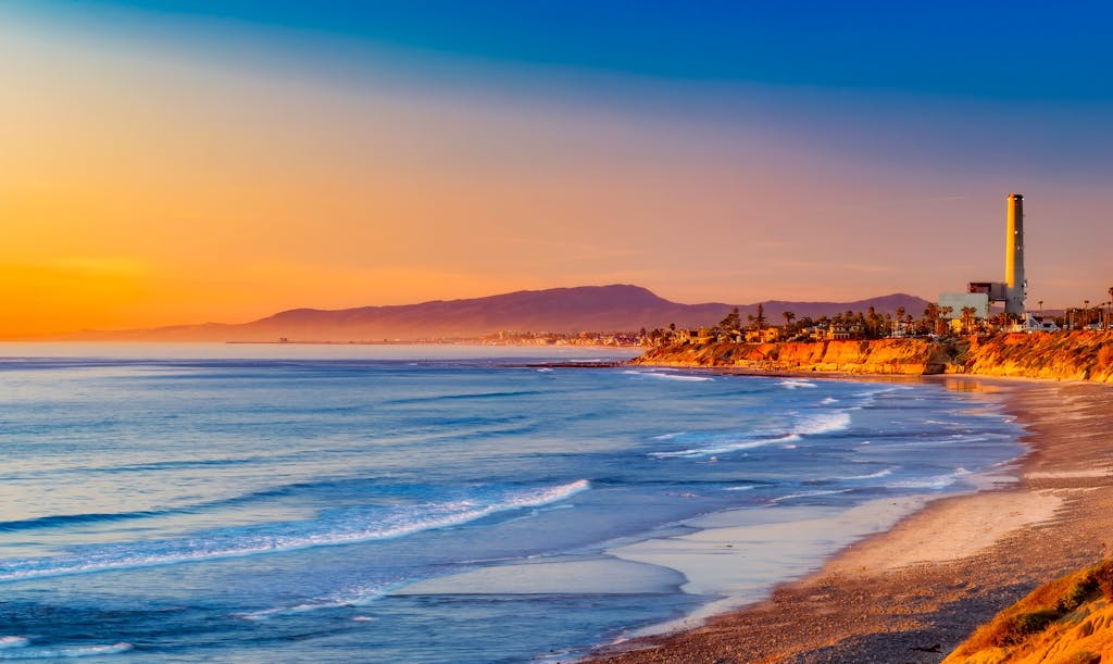 Sotwe Golden sunset over a serene California coastline, with rolling waves meeting the sandy shore.