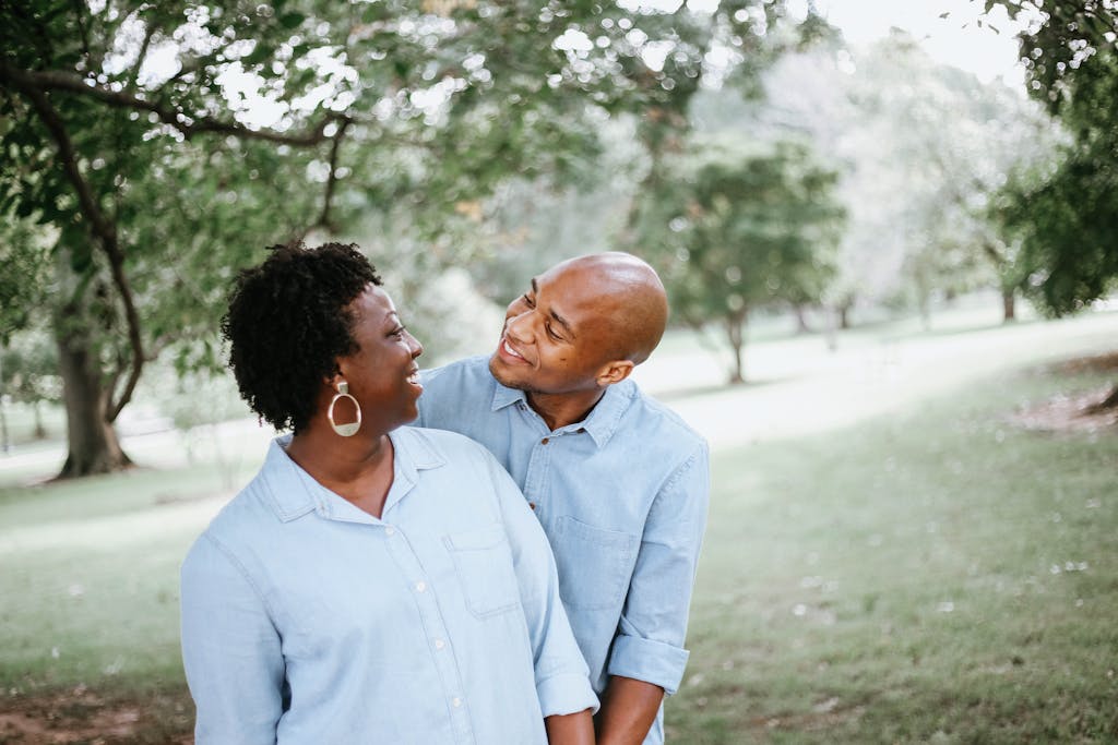 Binuscx Happy couple enjoying a playful moment together in a sunny park setting.