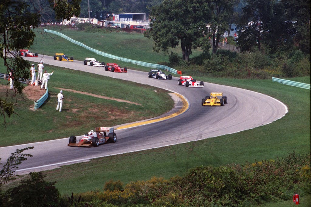 Drivers Death USA High-speed race cars on a curving track at Elkhart Lake, capturing motorsport excitement.