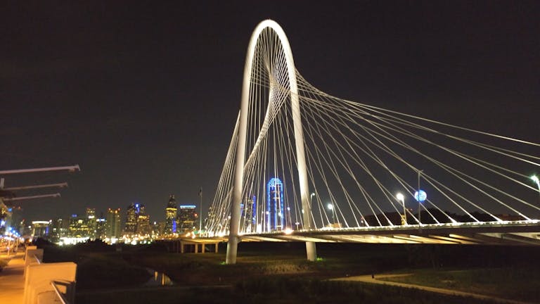 Texas Hunting Forum Iconic Dallas skyline featuring the illuminated Margaret Hunt Hill Bridge at night.