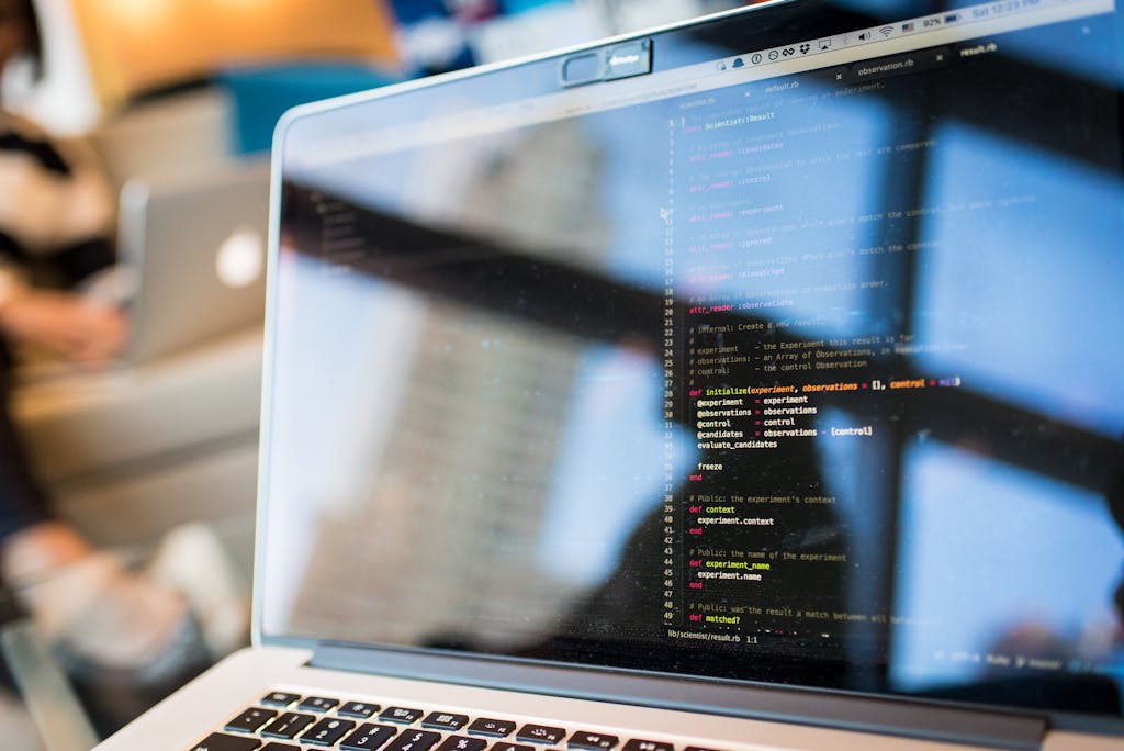 HR Software Laptop displaying code with reflection, perfect for tech and programming themes.