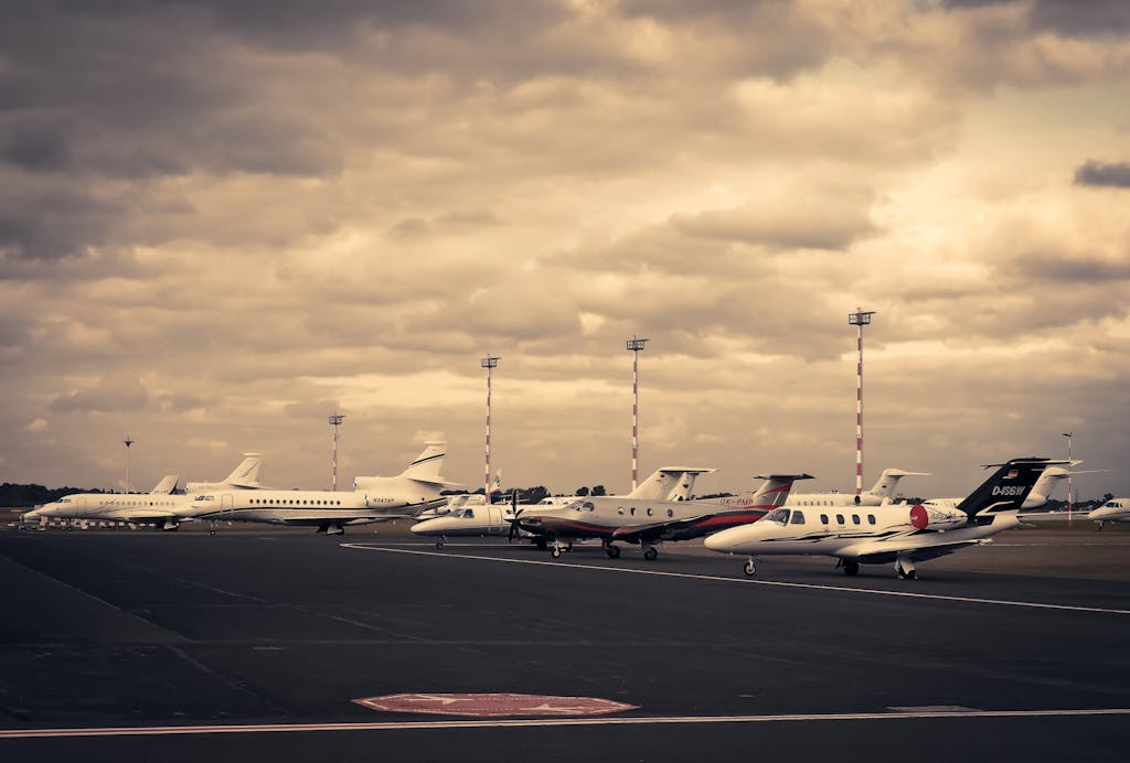 VirtusPlays Line of private jets parked on the tarmac under a dramatic cloudy sky, showcasing aviation and travel.