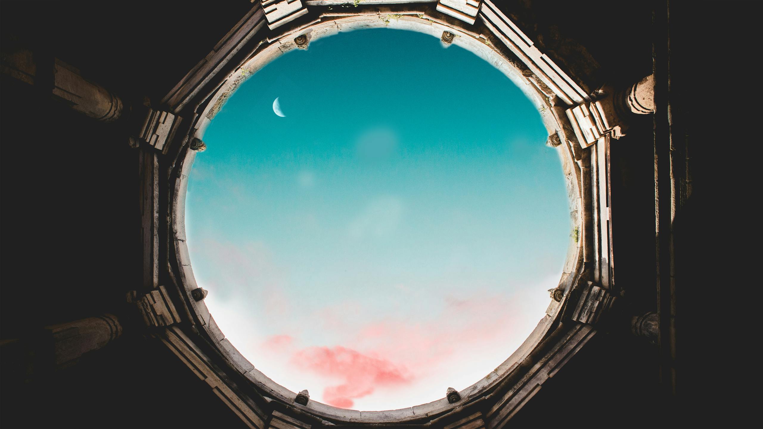 Lufanest Majestic crescent moon visible through an ancient round oculus against a vibrant sky.