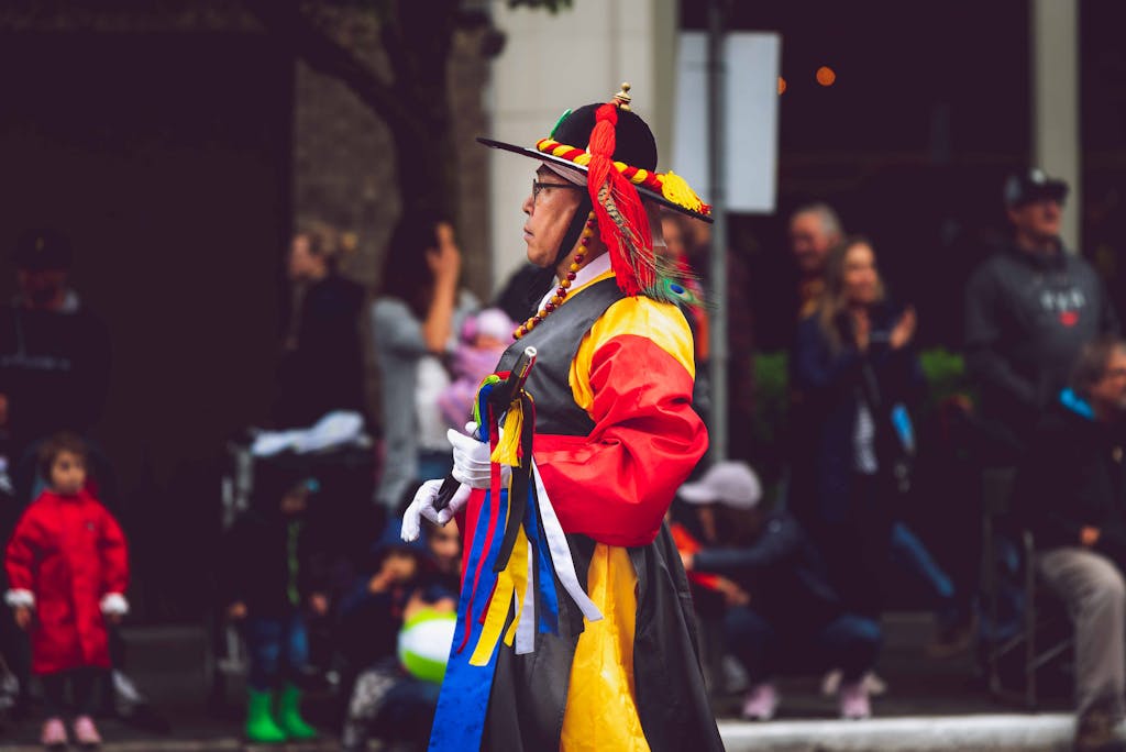 Koriandri Man in traditional Korean attire during a vibrant street festival parade outdoors.