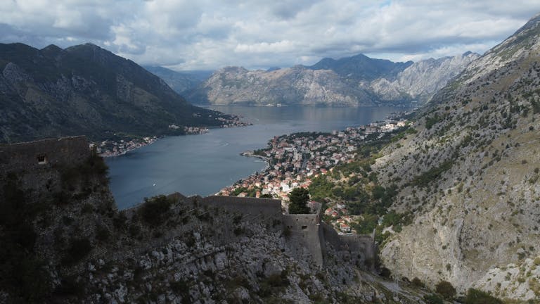 Kotora Melnkalne Scenic aerial view of Kotor Bay, Montenegro with surrounding mountains and historic castle ruins.