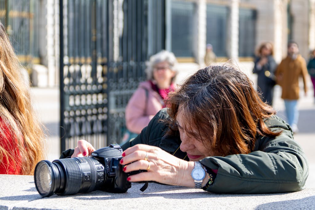 Serlig Senior woman setting up her camera outside in Madrid, capturing architectural beauty.