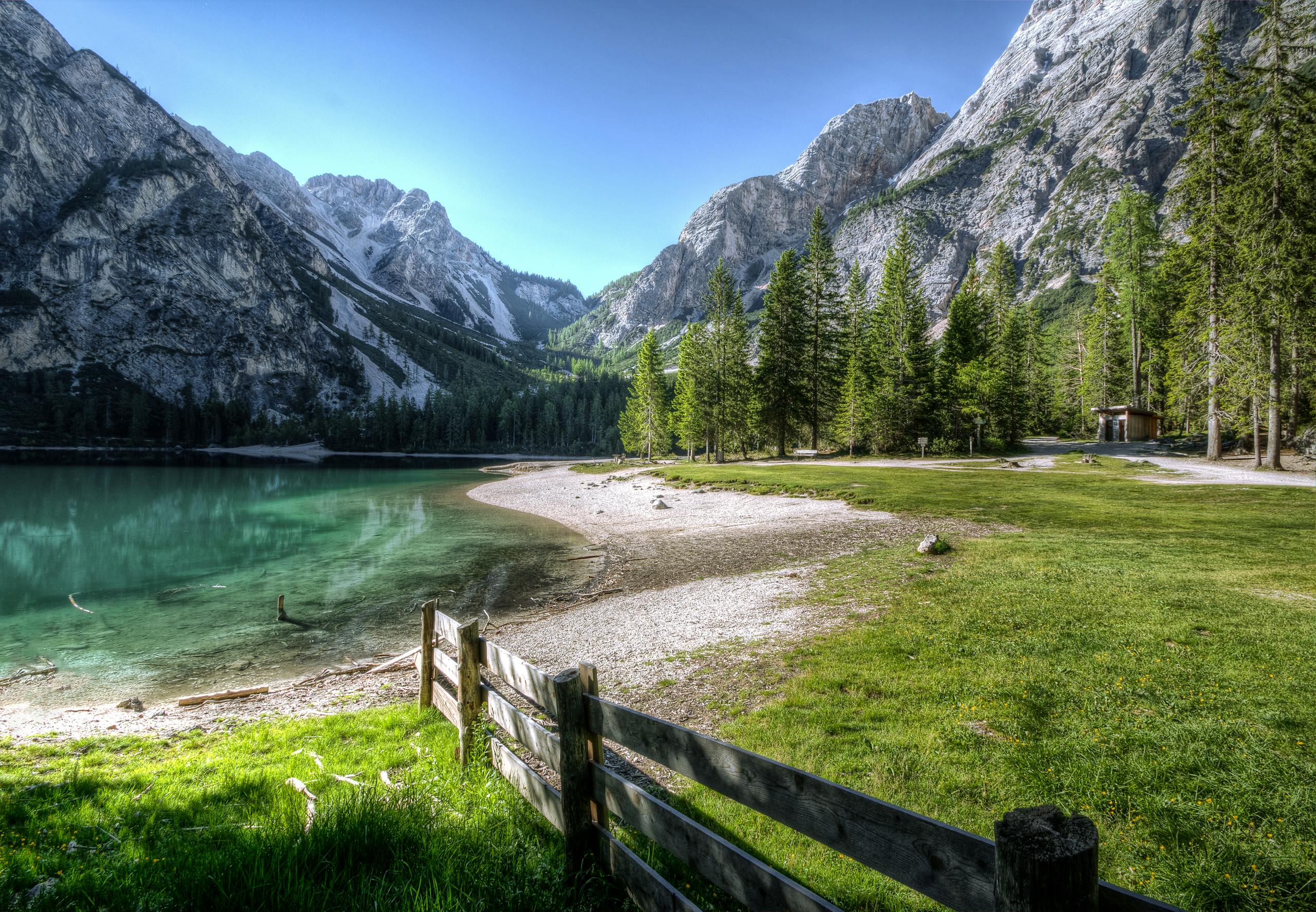 Gonzay Cartetach Serene mountain lake with green trees and a rustic fence, perfect nature backdrop.