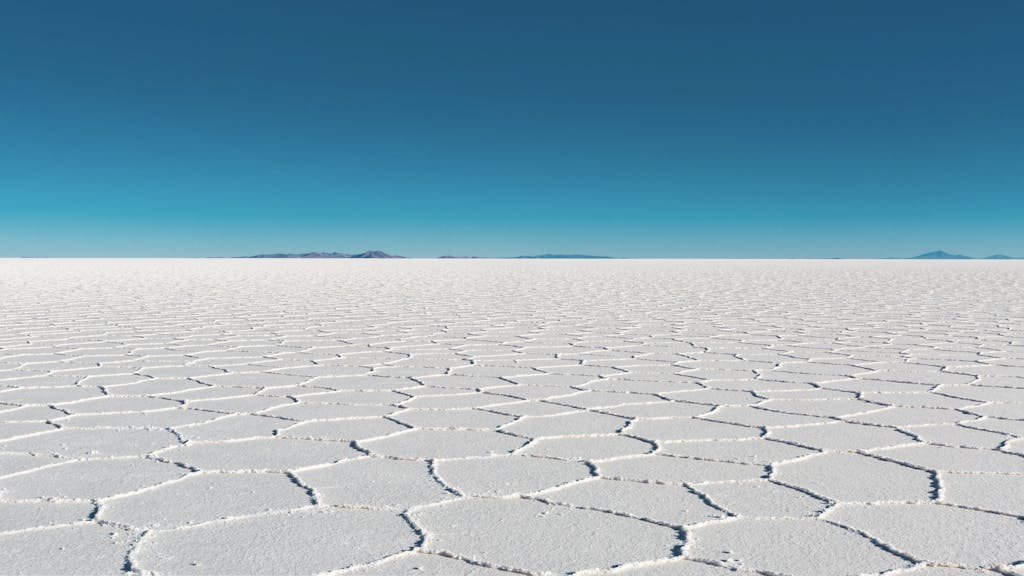 Darlnaija Vast salar with geometric patterns under a clear blue sky in Bolivia's Uyuni.