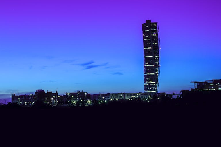 SKNews Vibrant night view of the Turning Torso skyscraper in Malmö, Sweden against a colorful sky.