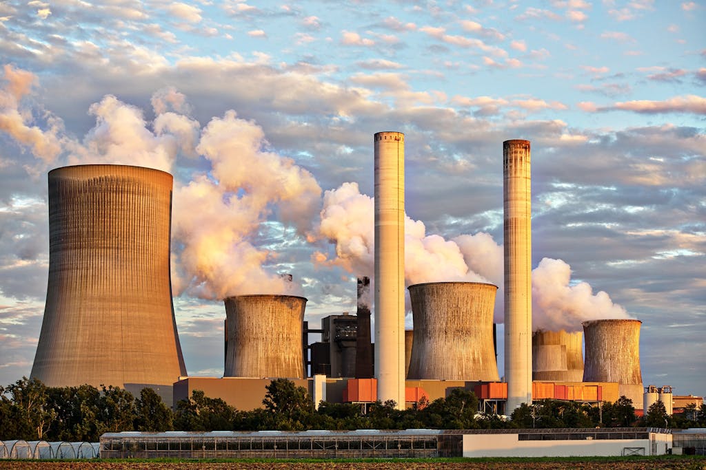 aiotechnical.com View of a power plant with smoke emissions under a cloudy sky, depicting industrial energy production.