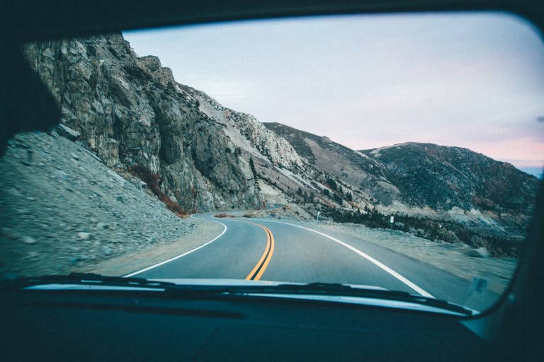 Gonzay View of a winding mountain road through a car windshield during a road trip.
