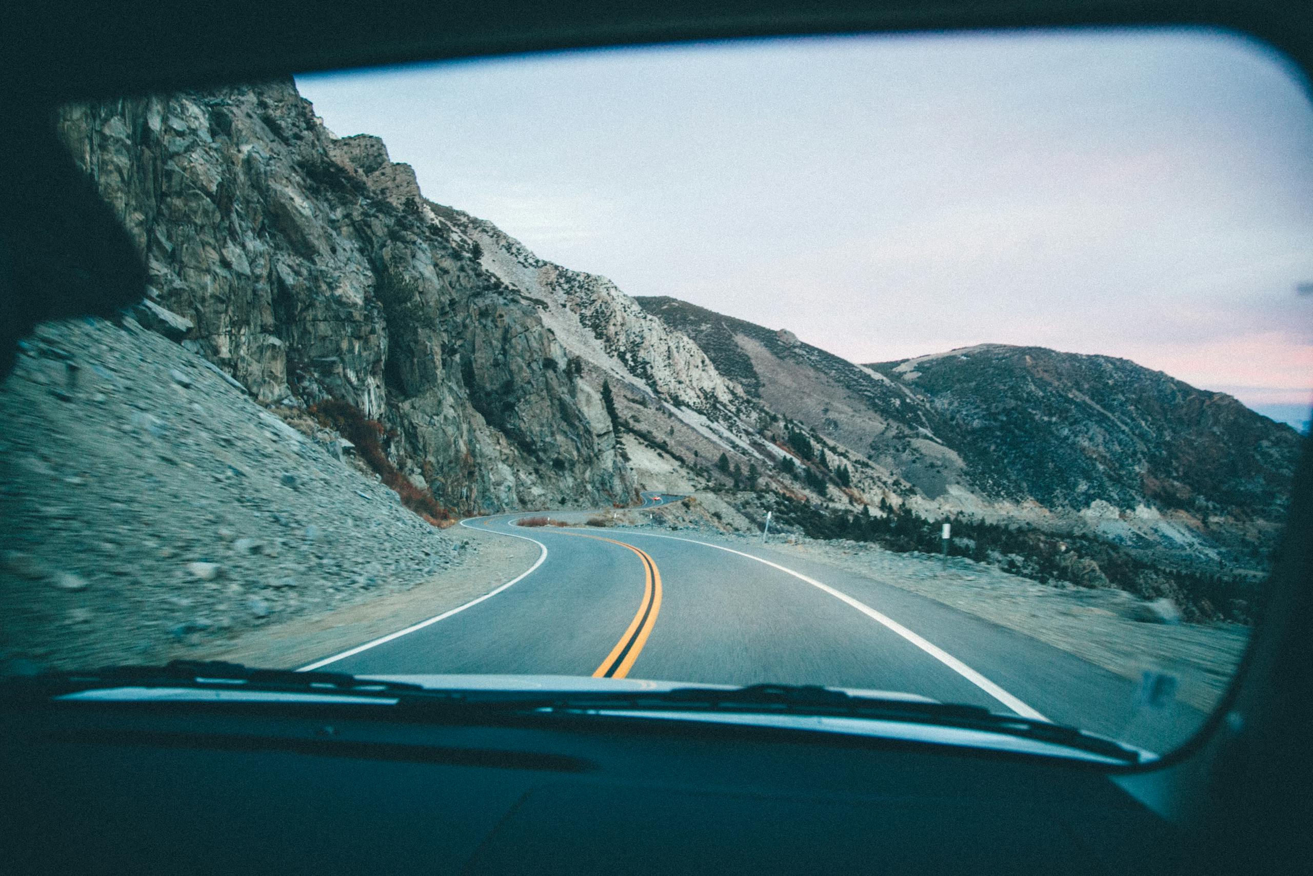 Gonzay View of a winding mountain road through a car windshield during a road trip.