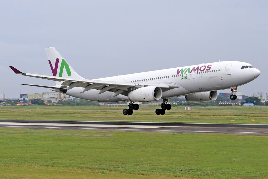 Akrylika Wamos Air Airbus A330 landing on the runway at a bustling airport.