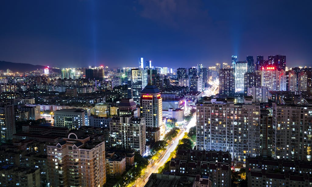 FintechAsia A vibrant night view of Fuzhou cityscape, featuring illuminated buildings and bustling streets.