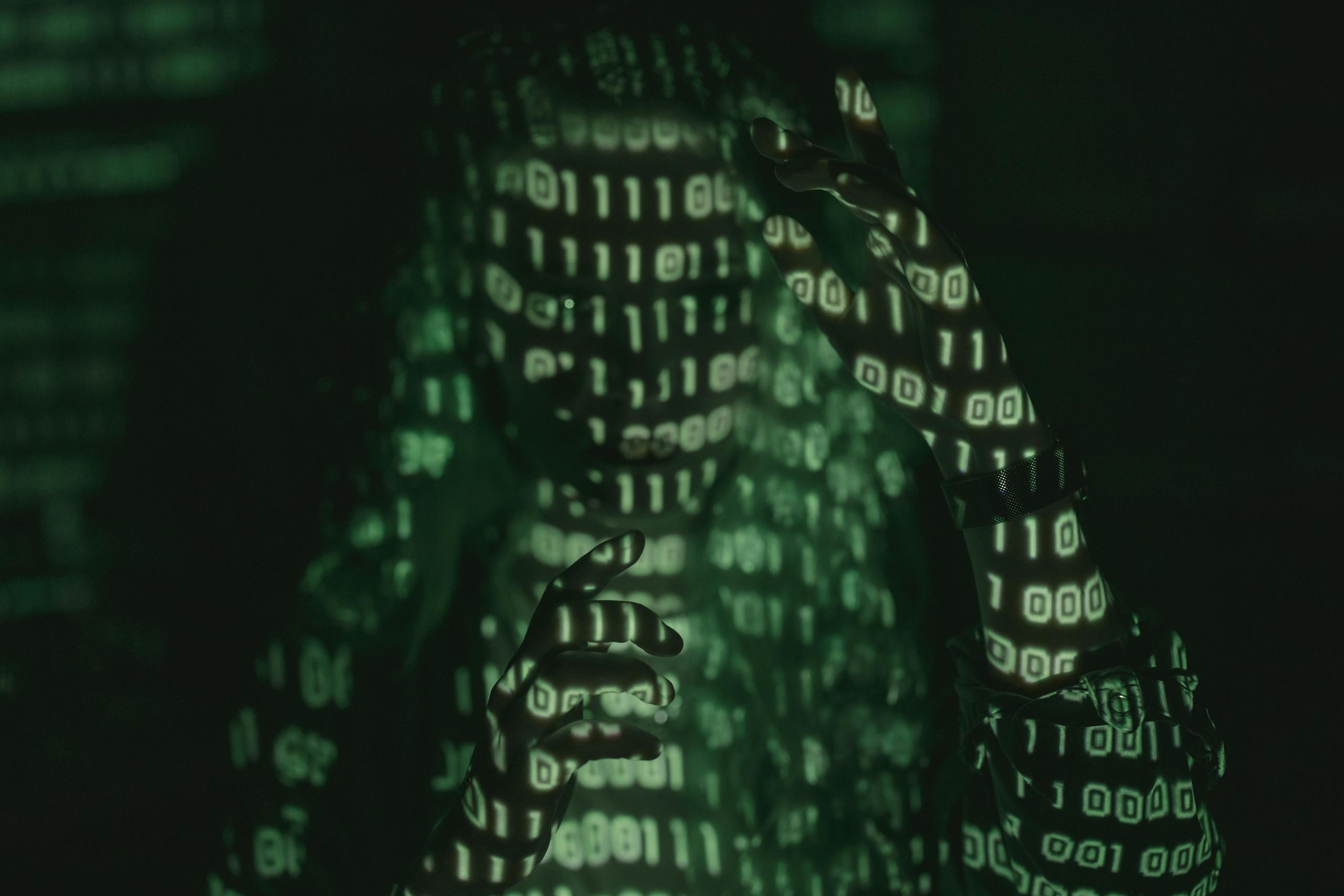 630 Area Code An unrecognizable person with binary code projected, symbolizing cybersecurity and digital coding.