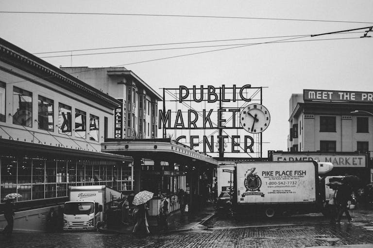 R6 Market PlaceBlack and white view of Seattle's Pike Place Market during rain, featuring iconic public market sign.